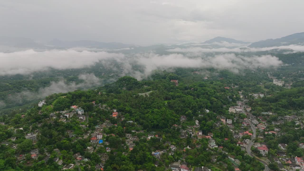 康提山迷人的鸟瞰图，以翠绿的风景和家园坐落在迷雾覆盖的山脉视频素材