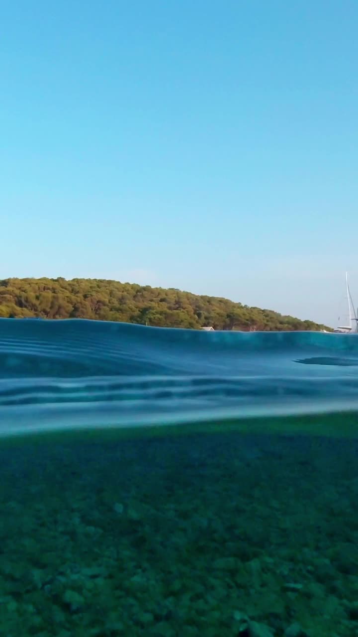 在一个阳光明媚的夏日，海湾里停泊着风景如画的游艇。上面和下面。垂直视频视频素材