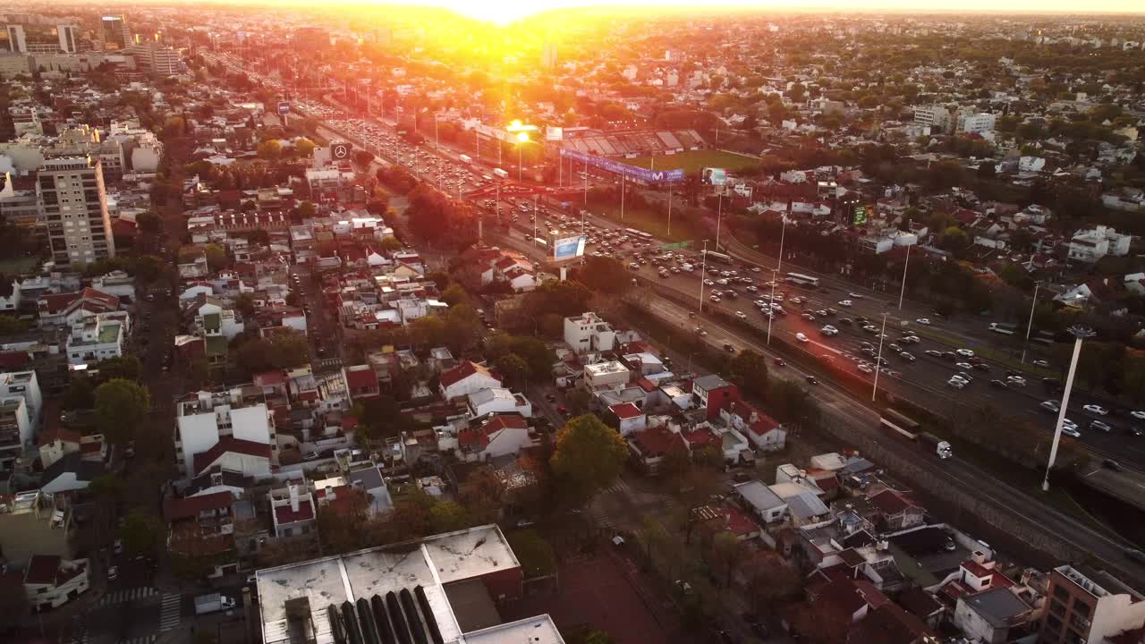 夕阳下的城市风光，无人机上的傍晚城市生活。繁忙的道路交通之间的建筑物，阳光视频下载