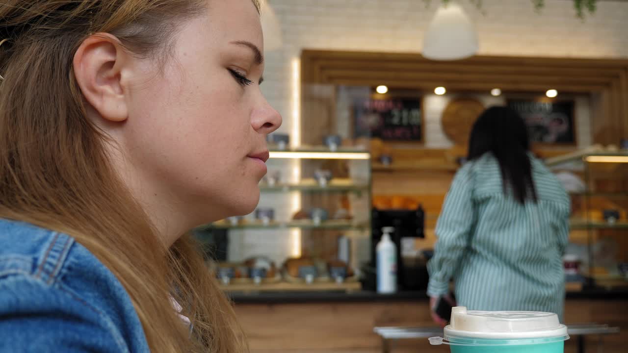 一个年轻女子早上在自助餐厅喝咖啡的特写。视频下载