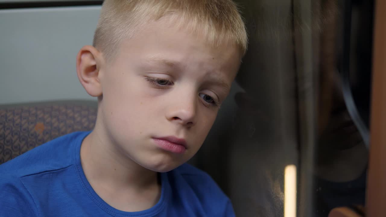 一个悲伤的小男孩在地铁车厢里的特写肖像。视频下载