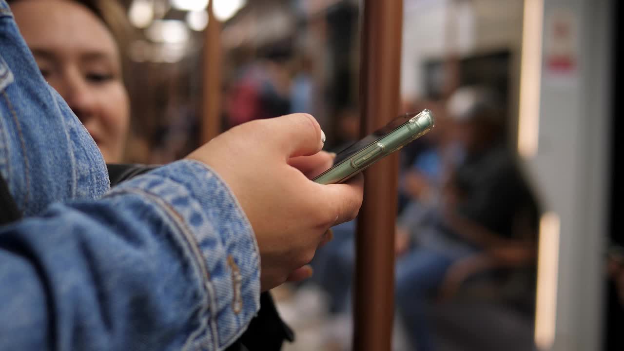 在地铁车厢里使用智能手机的女人的手特写。视频下载