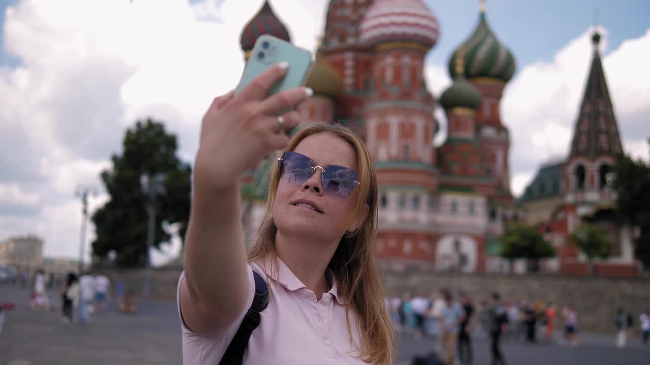 一名女子站在红场上，以教堂为背景自拍视频下载