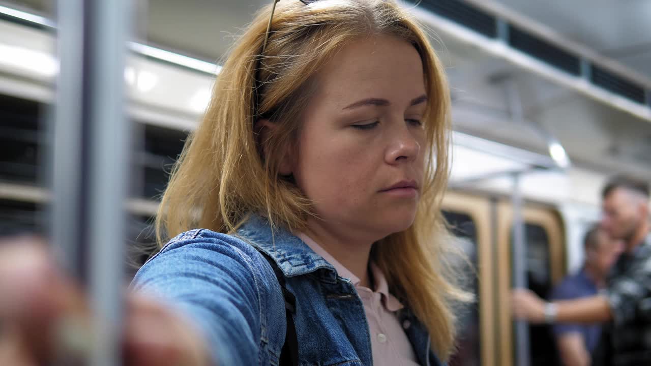 一个疲惫的女人在地铁车厢里的特写镜头，她站着睡觉。视频下载