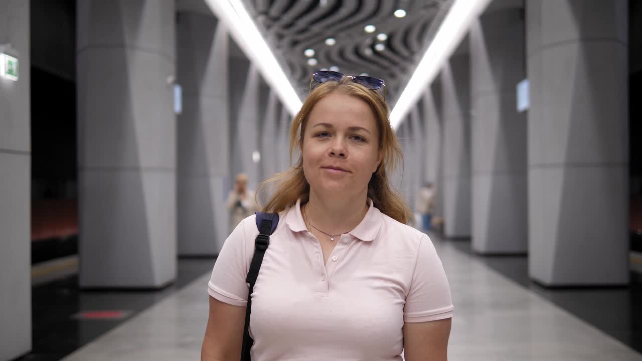 一个背着背包的年轻女子走过一个现代化的地铁站。视频下载