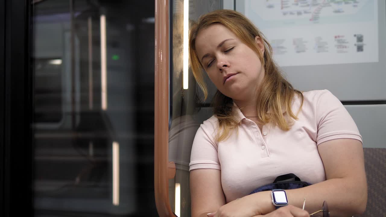 一个年轻疲惫的女人在地铁车厢里睡觉。视频下载