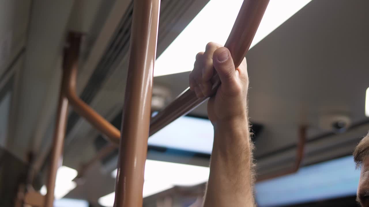 一名男子在地铁车厢里抓住扶手的特写镜头。视频下载