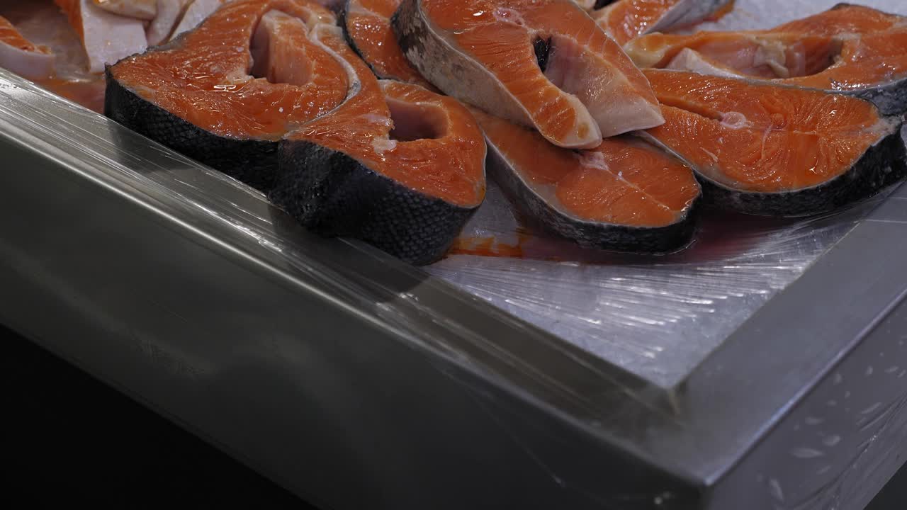 超市货架上鲜鱼去皮切片的特写。视频下载