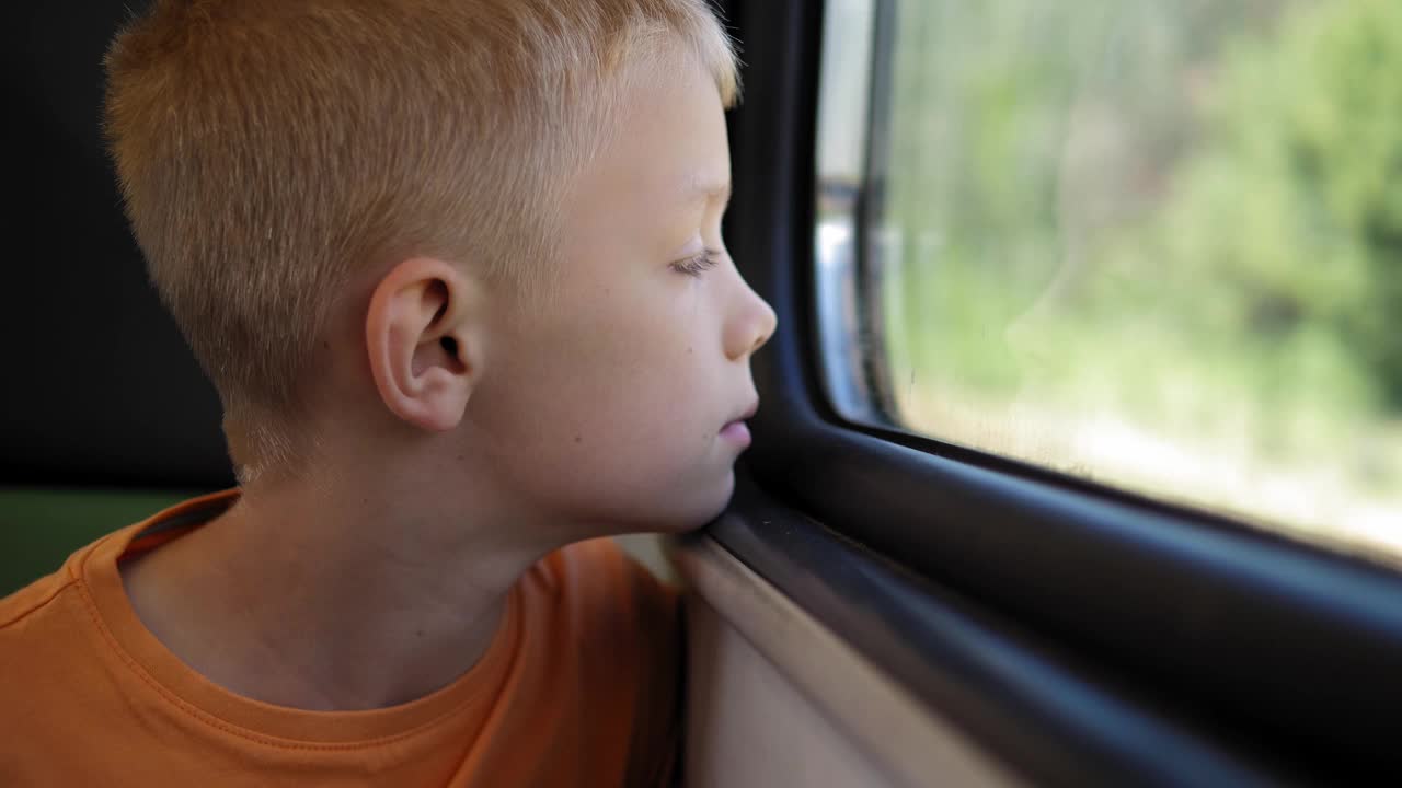 一个小男孩坐在火车上看着窗外的特写。视频下载