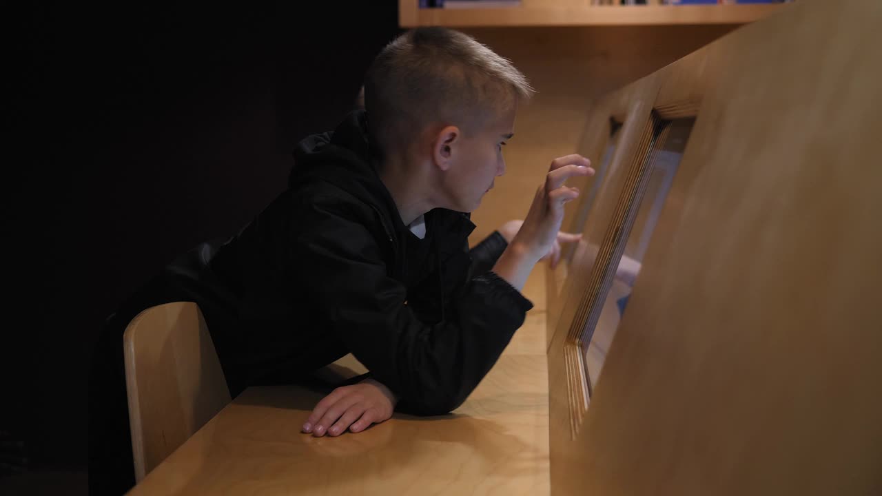 两个孩子坐在图书馆的电子平板电脑前。视频下载
