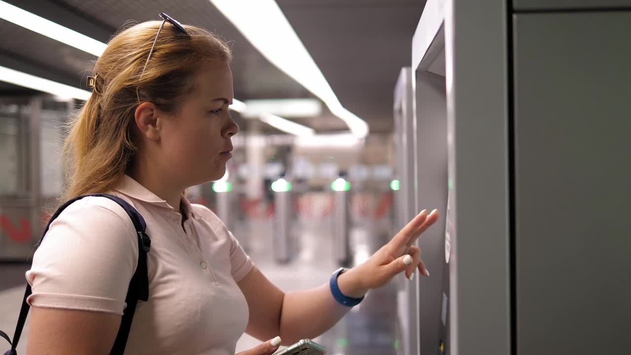 一位年轻女子在地铁站的自动贩卖机前买了一张地铁票。视频下载
