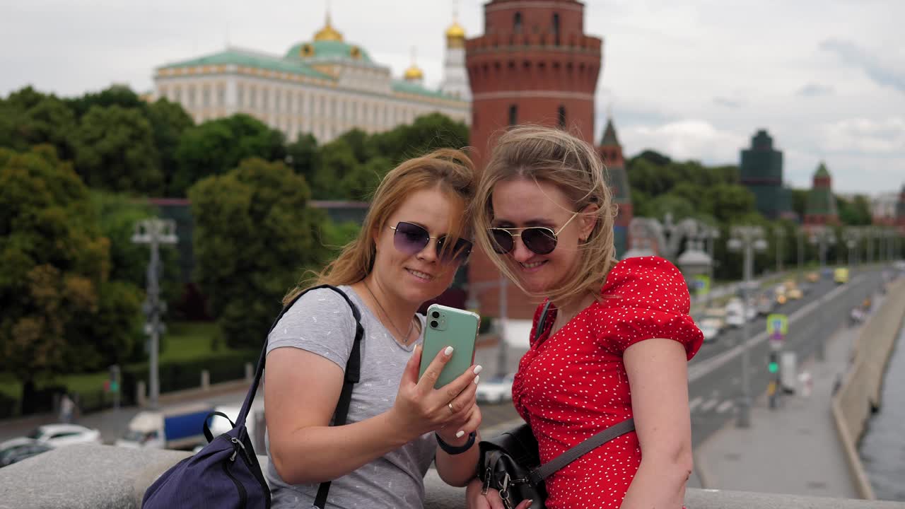 两个戴着墨镜微笑的年轻女子站在桥上自拍。视频下载
