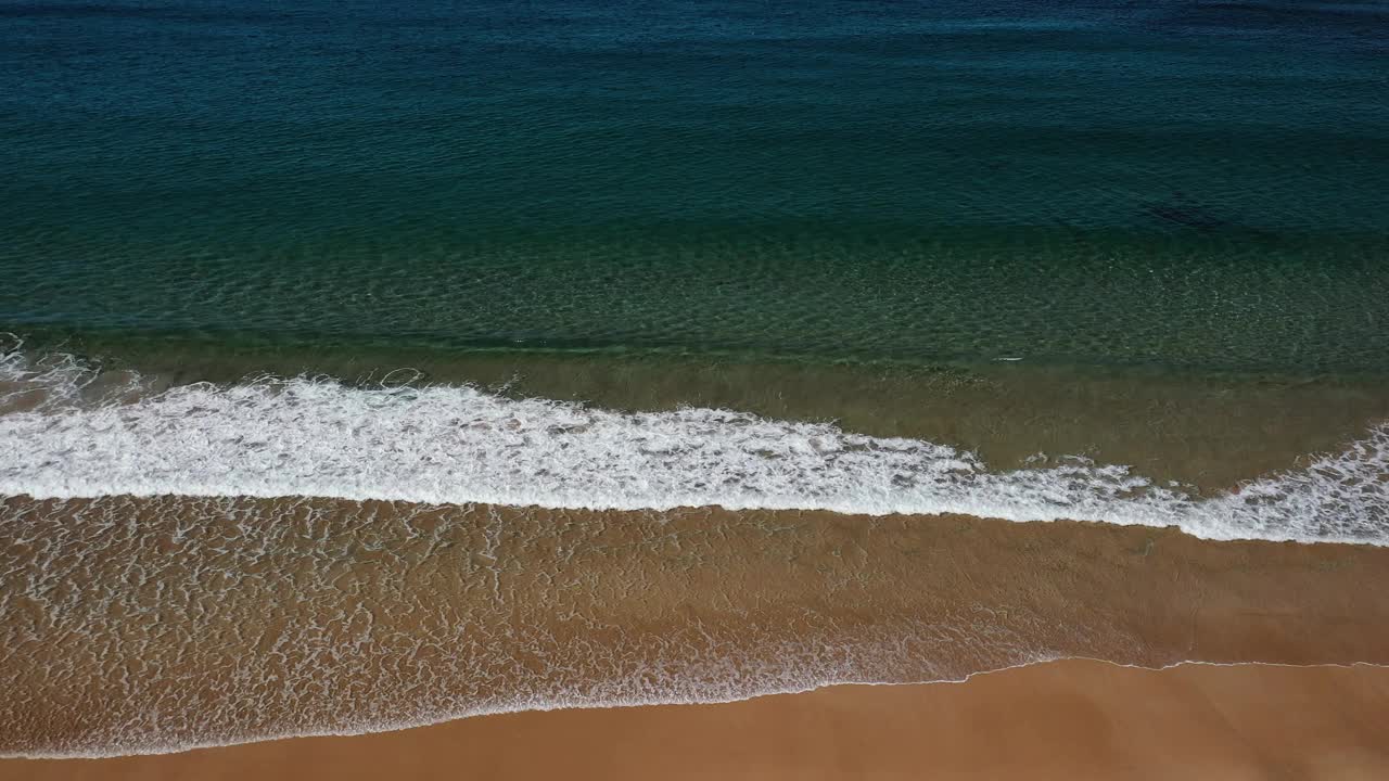 鸟瞰图，沿着金色的海岸，波浪在浅浅的清澈的水中破碎视频素材