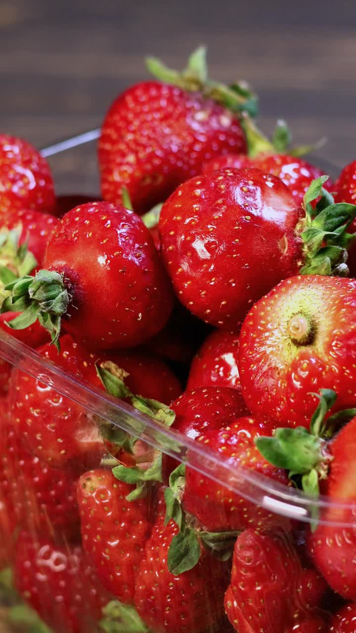 把新鲜的红草莓放进包装盒里。关闭了。垂直的画面。视频下载
