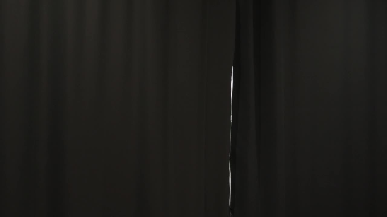 一个女人在卧室里打开遮光窗帘以吸收日光的背影。视频下载