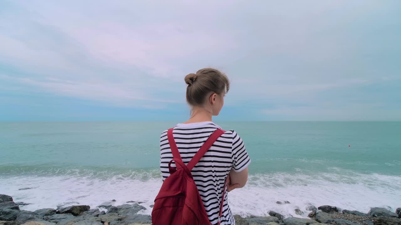 女人站在岩石岸边，看着惊涛骇浪视频素材