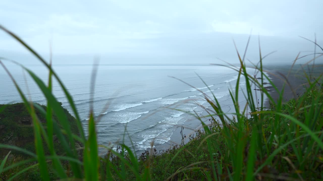 海景峭壁上美丽的绿草。夹。景观的岩石海岸与绿色的草和海洋地平线在阴天。从山海岸到美丽的海浪在夏天的一天视频素材