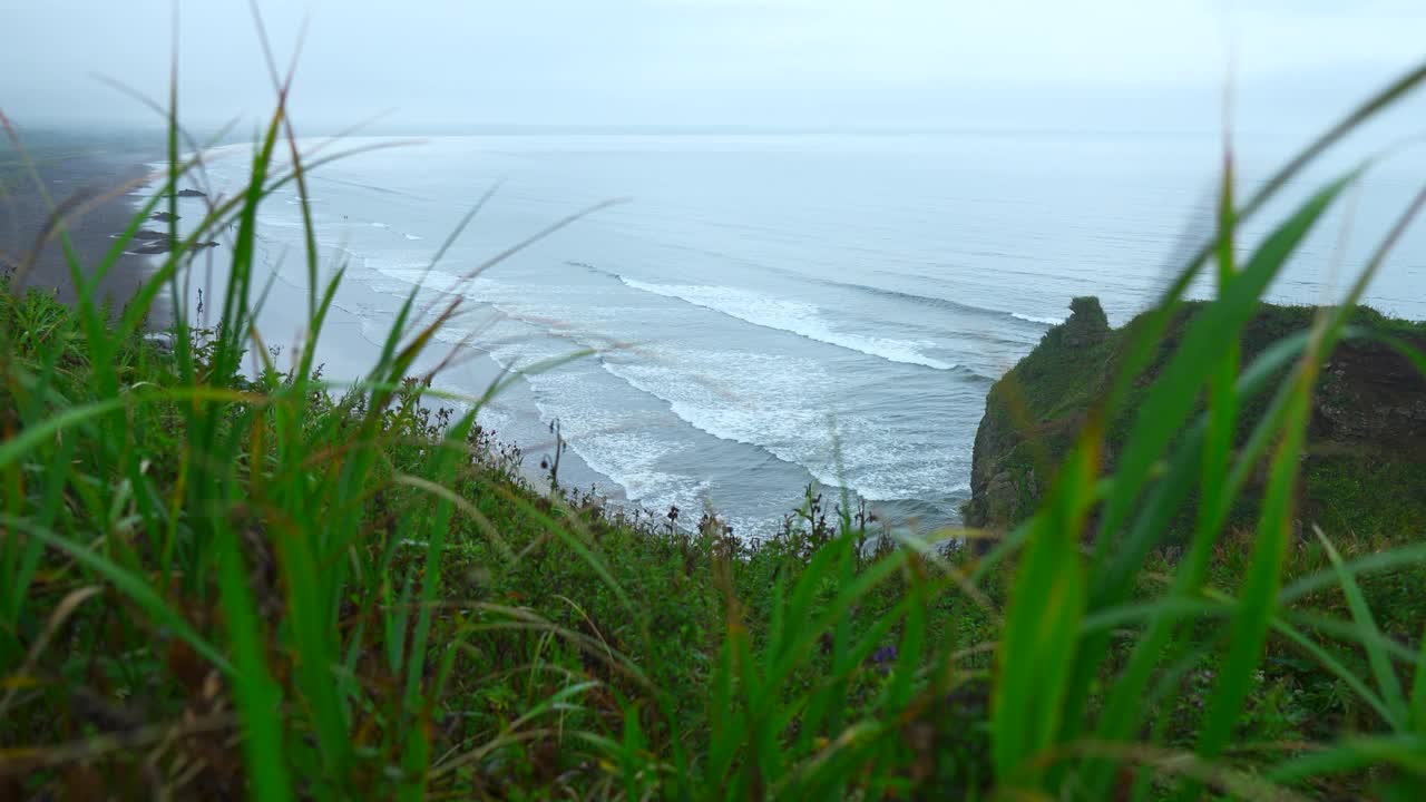 海景峭壁上美丽的绿草。夹。景观的岩石海岸与绿色的草和海洋地平线在阴天。从山海岸到美丽的海浪在夏天的一天视频素材