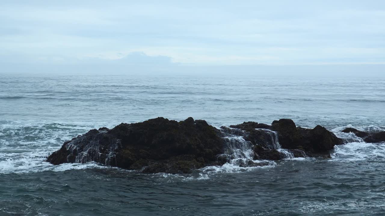 海岩石与移动的波浪在背景多云的地平线。夹。在阴天的海边，岩石突出在水面上。阴天里美丽的海景和岩石。视频素材