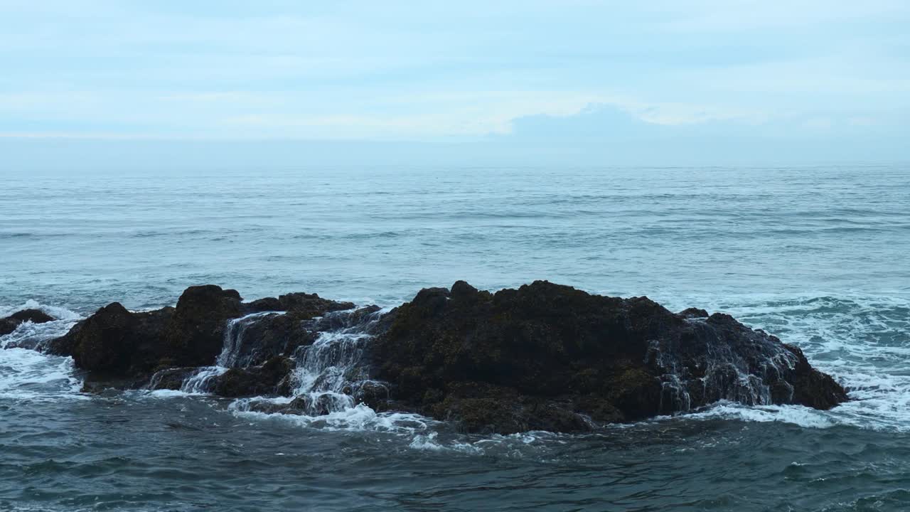 海岩石与移动的波浪在背景多云的地平线。夹。在阴天的海边，岩石突出在水面上。阴天里美丽的海景和岩石视频素材