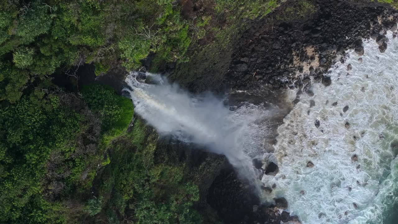 高大的瀑布在沿海热带岛屿的黑岩湾喷涌而出，海浪哗哗作响视频素材