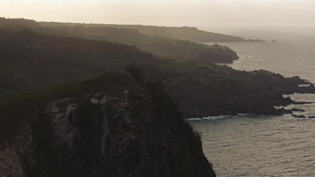 黄金时间的晚霞在西毛伊岛北岸陡峭的岩石崎岖的海岸线上蔓延，航拍视频素材