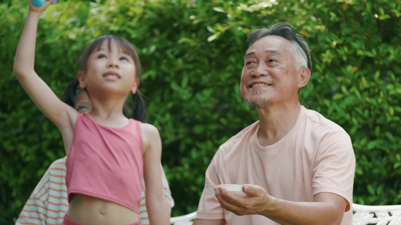 一对退休夫妇喜欢和他们的孙女一起玩泡泡。视频素材