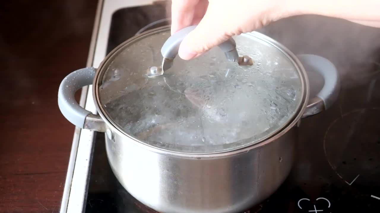 厨师把意大利面放进一锅沸水里。手和意大利面条的特写视频下载