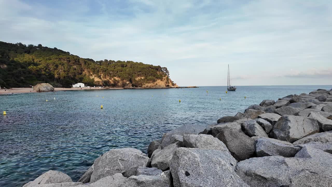 美丽的海景，日落时西班牙空旷的海滩，背景是地平线上的一艘帆船视频素材