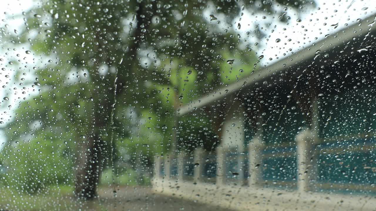 透过挡风玻璃外的雨滴从车内看到的特写。视频素材