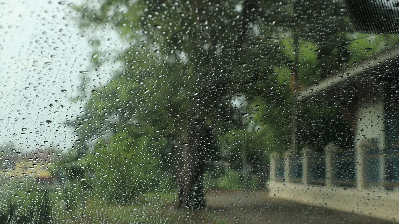 透过挡风玻璃外的雨滴从车内看到的特写。视频下载