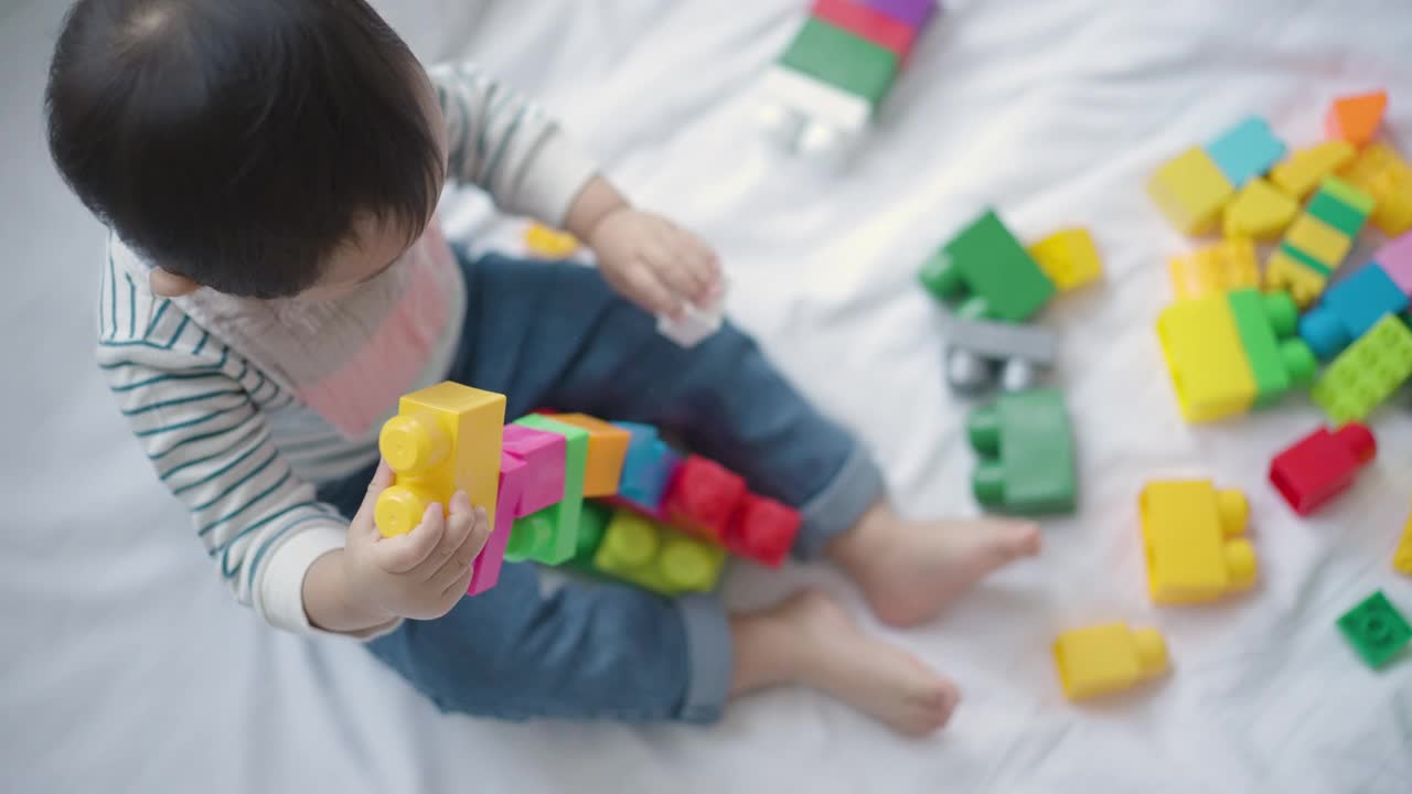 小男孩在家里卧室的床上玩积木玩具视频素材