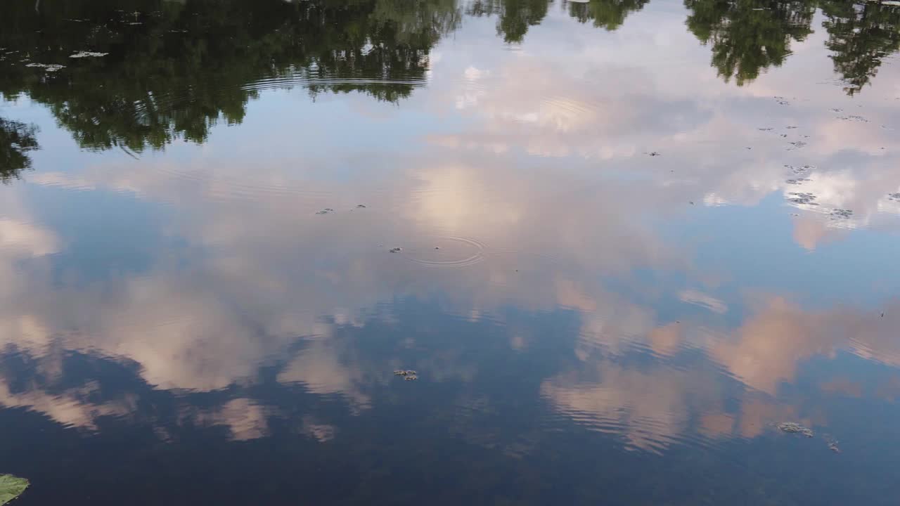 傍晚天空的蓬松的云反射在水面上，河的表面。视频下载