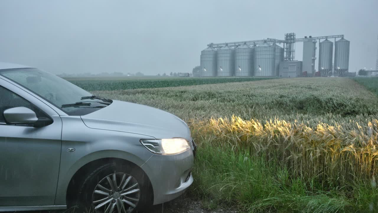 雨季农用粮仓背景下停在田间的汽车视频素材