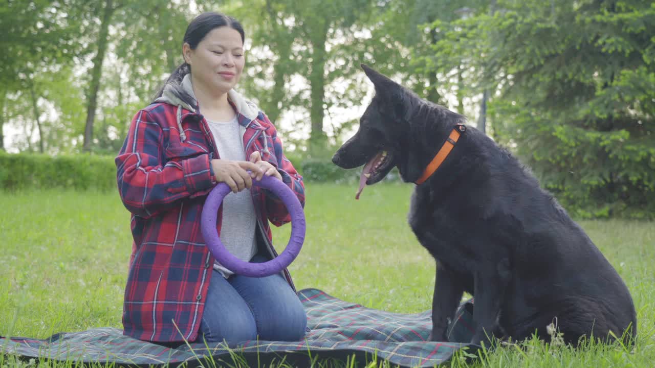 开朗成熟的亚洲女性宠物主人在公园里牵着狗玩拉车视频素材