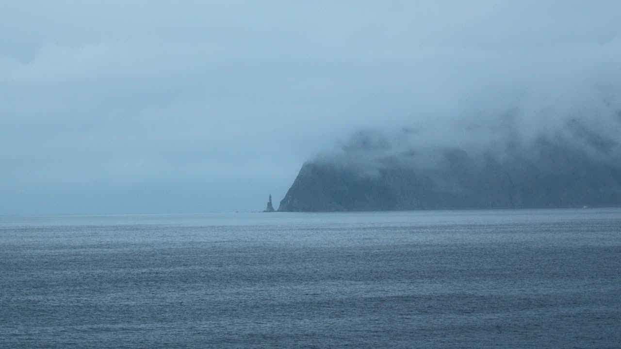 令人惊叹的岩石海景和低云。夹。在多云的天气里，蓝色的大海和深色的海岸岩石。电影般的海景，戏剧性的低云覆盖着海岸的悬崖视频素材