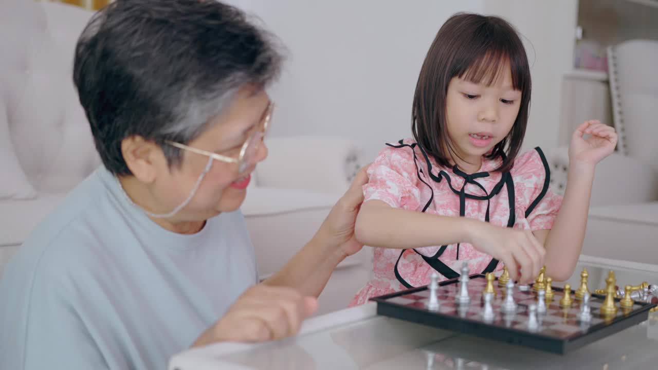 老夫妇和孙女在家里下棋，一起享受视频素材