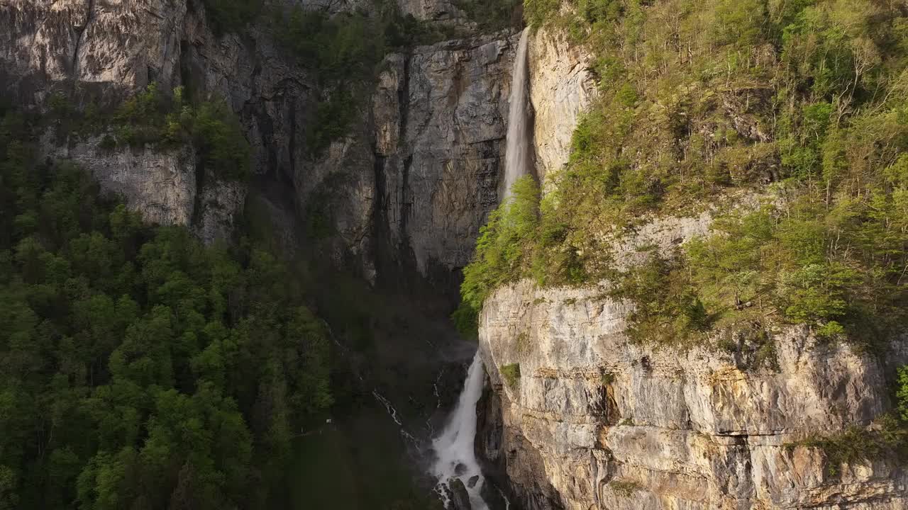 Seerenbach瀑布鸟瞰图，瀑布从崎岖的悬崖上倾泻而下，周围环绕着郁郁葱葱的绿色植物，位于瑞士阿姆登市的Betlis附近。视频素材