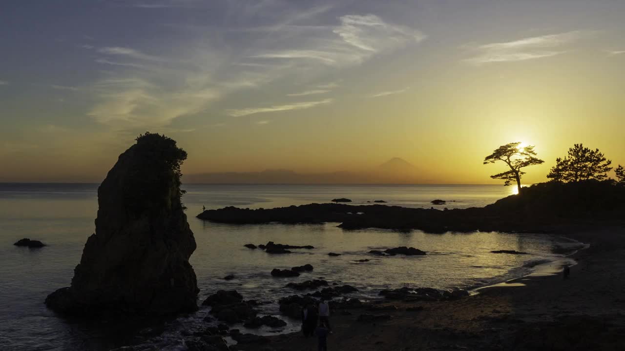 从横须贺秋泰石海滩和被夕阳染红的富士山拍摄的日落在海洋上的延时视频下载