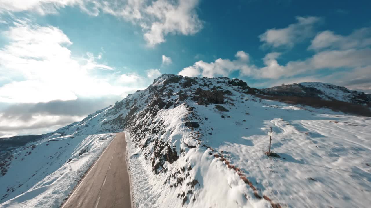 无人机拍摄的白雪覆盖的山路和晴朗的蓝天视频素材