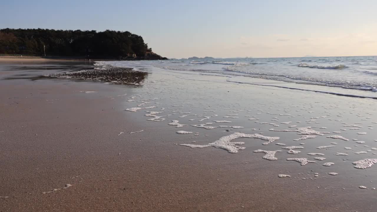 傍晚时分，柔和的海浪涌向海滩。视频素材