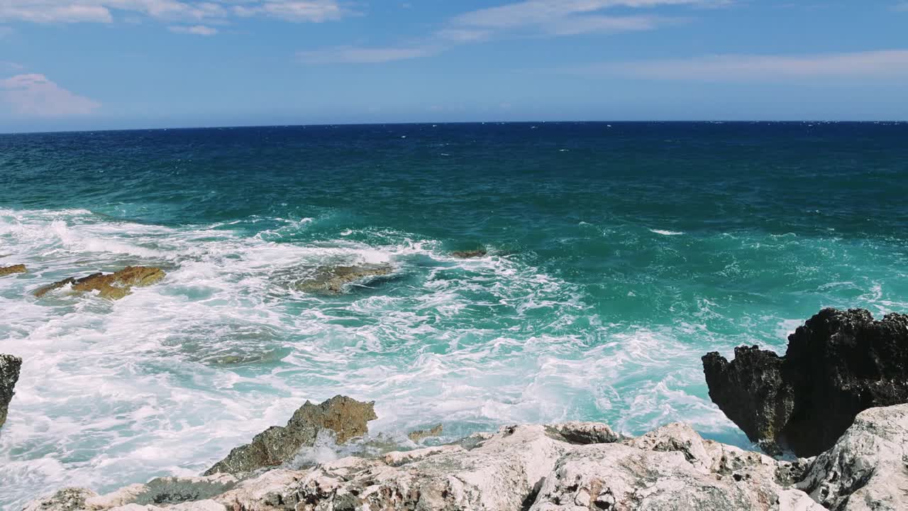 宁静的边缘:一瞥绿松石海体验海洋的原始力量和美丽，因为绿松石海浪撞击岩石悬崖。视频素材