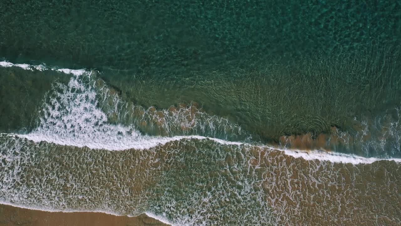 鸟瞰图，沿着金色的海岸，波浪在浅浅的清澈的水中破碎视频素材