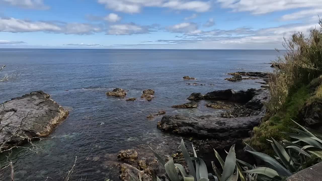 亚速尔群岛圣米格尔卡罗胡拉的岩石海岸线，湛蓝的海水在多云的天空下视频素材