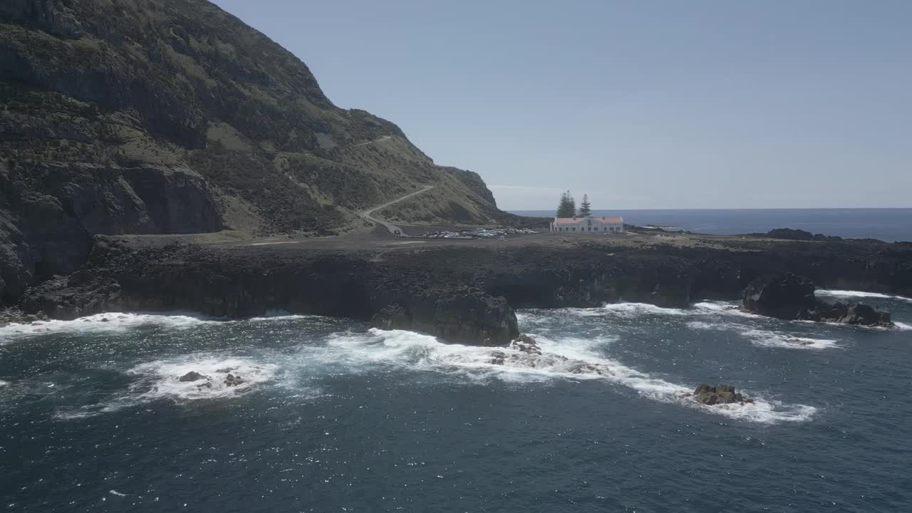 灯塔矗立在岩石海岸，在阳光明媚的日子里海浪汹涌视频素材