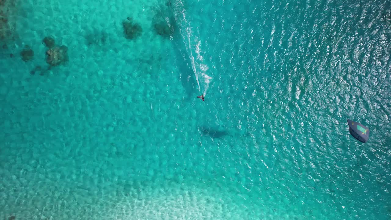 一个风筝冲浪者在热带岛屿附近清澈的水面上滑翔，鸟瞰图视频素材