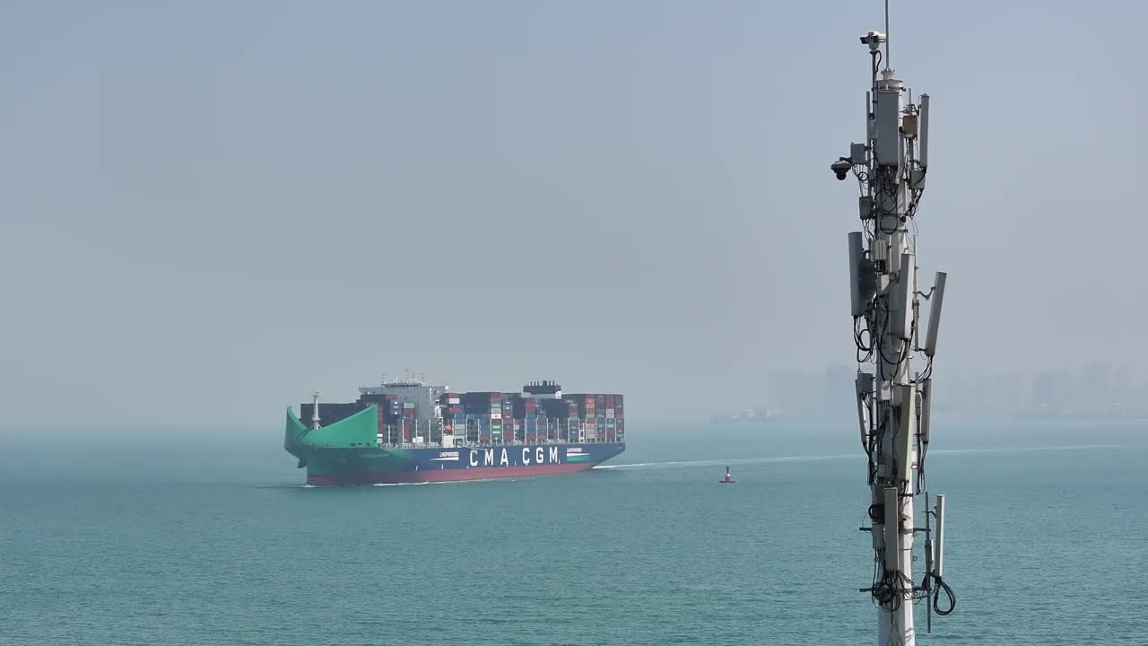 实时-原始画面:CMA CGM BUZIOS集装箱船在5G通信塔前航行的无人机鸟瞰图视频素材