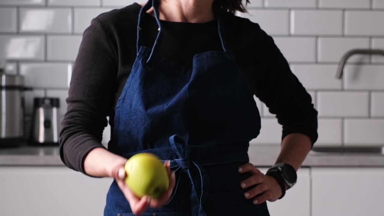 穿围裙的女人在厨房里扔接生青苹果视频下载