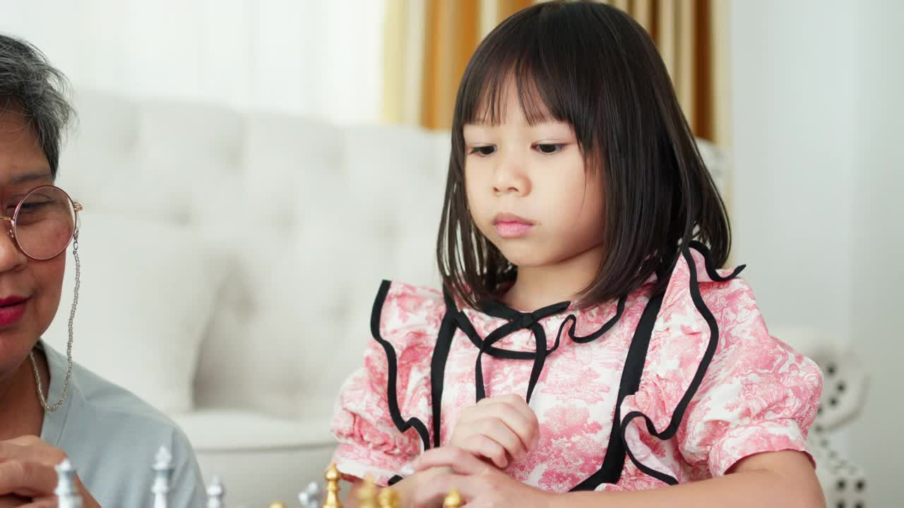 奶奶和孙女在家里下棋一样享受，节日里快乐的友谊活动;视频素材