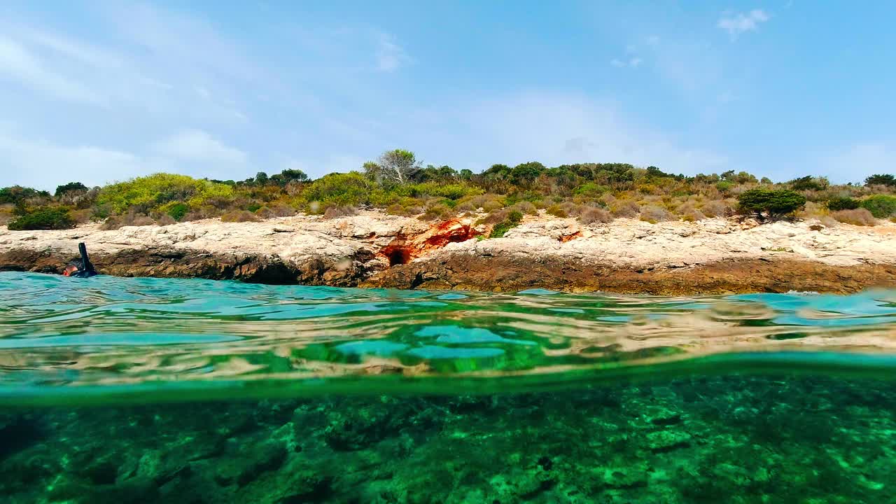 度假期间，一名男子在亚得里亚海的岩石海岸附近浮潜。克罗地亚阳光明媚的夏日视频素材